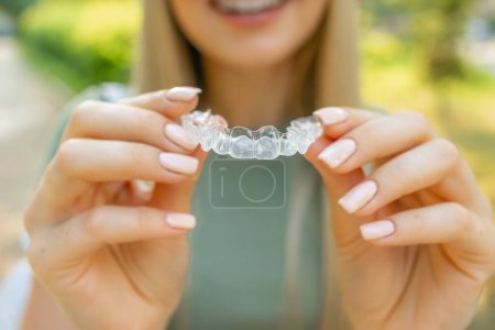 Foto de Primer plano del alineador de dientes transparentes de silicona ortodóncica en manos femeninas. - Imagen libre de derechos