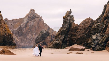 Téléchargez les photos : Jeunes mariés s'amusant et marchant sur le fond de rochers massifs en pierre
. - en image libre de droit