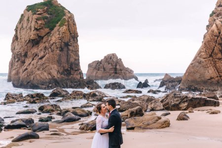 Photo for High cliffs and lots of stones in seawater. newlyweds hug and look at each other. - Royalty Free Image