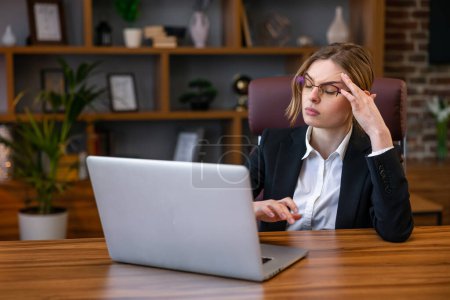 Photo for Stressed and tired young woman with headache at workplace - Royalty Free Image