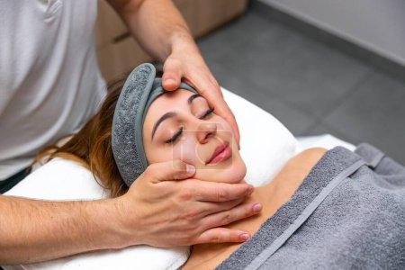 Photo for Facial massage. Close-up of young woman getting massage at spa salon.Spa care for skin and body. Facial beauty care. Cosmetology. - Royalty Free Image