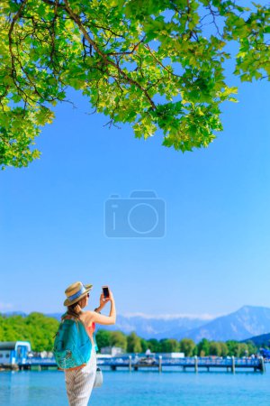 Photo for Back view of girl with a backpack and boater do photos lake in mountains. - Royalty Free Image