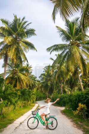 Téléchargez les photos : Fille avec un vieux vélo vintage sur un fond de palmiers. jeune femme dans la jungle de la forêt tropicale avec des palmiers. activités touristiques et touristiques détendues vacances d'été - en image libre de droit