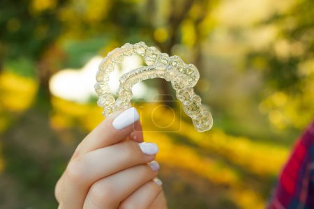 Foto de Mano femenina sosteniendo Invisalign, el alineador de frenos invisible en el fondo verde. Corrección del concepto de dientes - Imagen libre de derechos