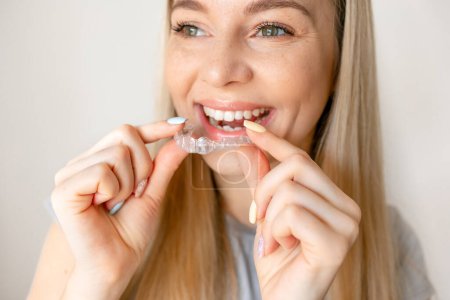 Photo for Young woman holding invisible aligner. Dental health, beautiful smile - Royalty Free Image