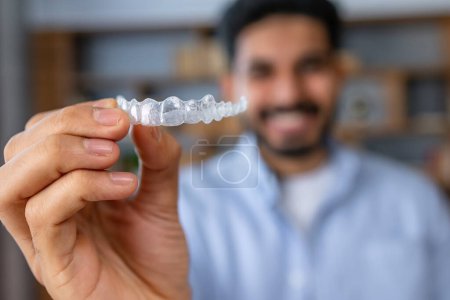 Foto de Hombre mostrando un alineador de silicona invisible para corrección dental. Mano masculina sosteniendo los retenedores de odontología de plástico para enderezar los dientes - Imagen libre de derechos