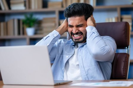 Foto de Árabe empleado sentirse estresado y serio de trabajo mientras está trabajando con el ordenador portátil en la oficina. - Imagen libre de derechos