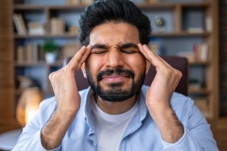 Téléchargez les photos : Migraine de travail stressant. Homme déprimé employé assis au bureau, serrant les tempes de la tête, souffrant de maux de tête et de tension, inquiet des problèmes au travail - en image libre de droit