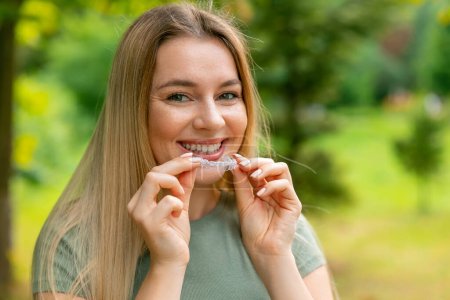 Photo for Close-up of a girl's hand putting transparent aligner in teeth - Royalty Free Image