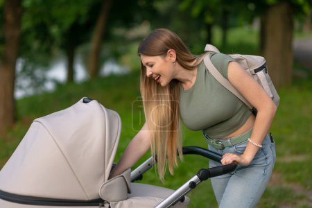 Closeup of mother with baby in pram walking in summer park
