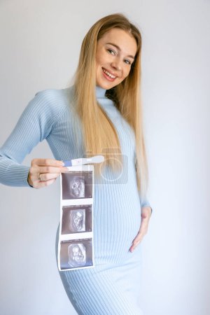 Foto de Mujer feliz sosteniendo positivo prueba de embarazo y ultrasonido imagen - Imagen libre de derechos