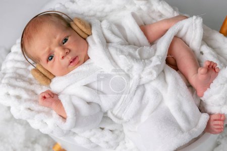Beautiful little infant baby boy dressed in white bathrobe and towel. Lifestyle instagram newborn concept. lies in a chair after spa treatments.