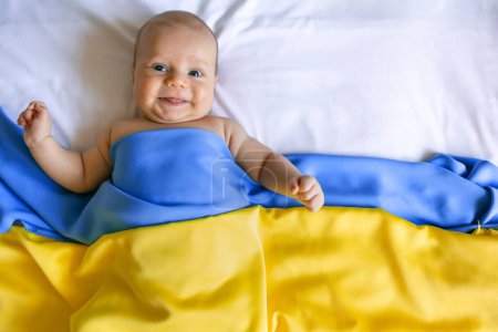 Foto de Un bebé cubierto desde arriba con la bandera azul-amarilla de Ucrania. El concepto de proteger a las familias. foto con lugar para el texto. - Imagen libre de derechos