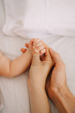 Photo for Close-up little hand of child and palm of mother and father. The newborn baby has a firm grip on the parent's finger after birth. A newborn holds on to mom's, dad's finger. - Royalty Free Image