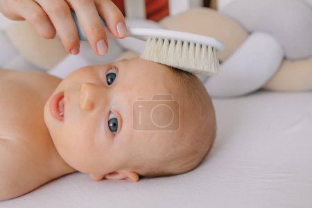 Photo for Mom gently combs the hair of her newborn baby - Royalty Free Image