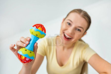 Foto de Una madre jugando con un juguete de sonajero de colores temblorosos. pov bebé. mira a la cámara - Imagen libre de derechos