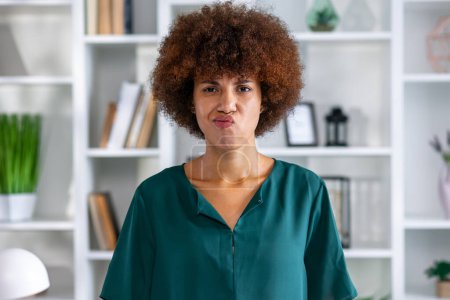 Photo for Young offended ethnic African American woman pouting looking at camera after bullying or insult or intolerance stands in office - Royalty Free Image