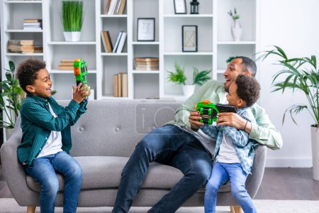 Téléchargez les photos : Homme riant tout en jouant avec des fils sur le canapé - en image libre de droit