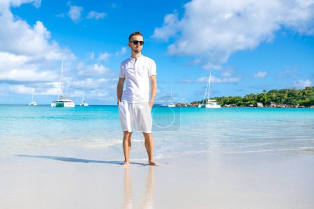 Foto de Hombre guapo con ropa blanca posando en el paisaje del mar - Imagen libre de derechos