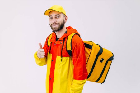 Photo for Smiling courier with thermal backpack smiles at the camera and shows thumbs up. - Royalty Free Image