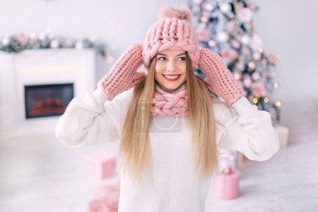 Photo for Closeup of a girl with freckles in a stylish hat, gloves and scarf. Christmas tree at home. close up. - Royalty Free Image