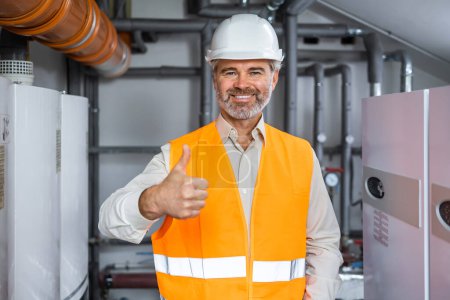 Photo for Portrait of petroleum refinery mature senior gray haired worker holding thumb up in gas distribution center or heating room - Royalty Free Image