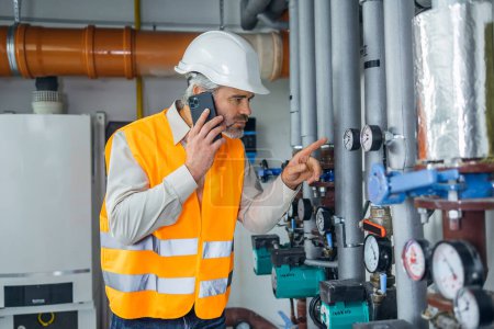 Photo for Engineer working in a thermal power plant and talking on the phone - Royalty Free Image