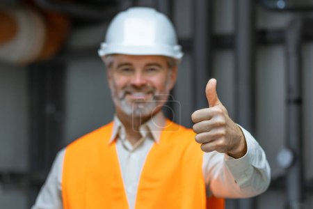 Photo for Portrait of factory worker or contractor holding thumb up in petrochemical industrial refinery. - Royalty Free Image