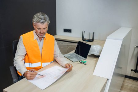 Photo for Portrait of Handsome Male Engineer Wearing Safety Vest Working on blueprints drafts, Developing pipes conditioning system. Architect project - Royalty Free Image