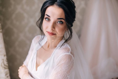 Téléchargez les photos : Mariée de luxe en robe blanche posant tout en se préparant pour la cérémonie de mariage - en image libre de droit