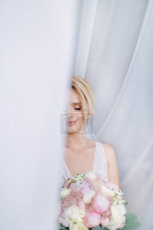 Téléchargez les photos : Mariée avant son mariage jetant un coup d'oeil à partir d'un rideau blanc. - en image libre de droit