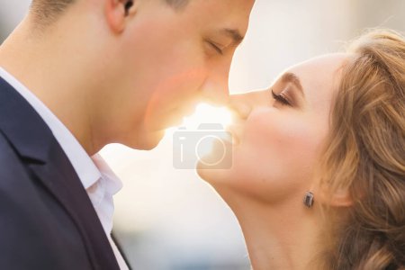 Téléchargez les photos : Les jeunes mariés fermèrent les yeux et penchèrent le nez et la lumière du soleil entre eux. gros plan. - en image libre de droit