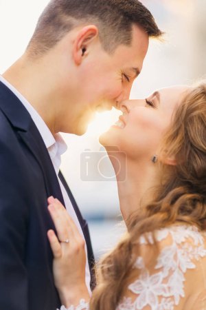 Photo for The newlyweds hugging and kissing on the city street. the sunlight between bride and groom. - Royalty Free Image