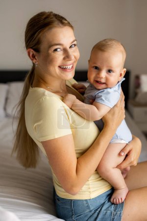 Foto de Retrato de maternidad. Joven hermosa madre amorosa sosteniendo lindo bebé niño expresando amor incondicional - Imagen libre de derechos