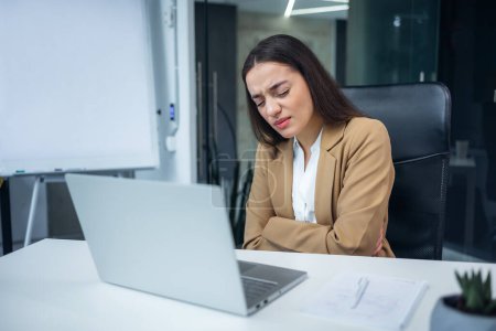 Téléchargez les photos : Femme d'affaires malade se sentant pms douleur sur le lieu de travail au bureau. Femme épuisée ayant des maux d'estomac aigus en travaillant à l'intérieur. Concept d'empoisonnement et de gastrite. - en image libre de droit