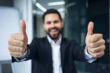 Photo for Positive young man showing thumb up sign over office background. Winner. Success. Body language. office background - Royalty Free Image