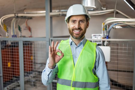 Photo for Handsome worker man wearing uniform and helmet smiling positive doing ok sign with hand and fingers. Successful expression. - Royalty Free Image