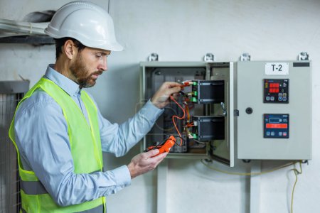 Téléchargez les photos : Un électricien masculin travaille dans un standard avec un câble de connexion électrique
. - en image libre de droit