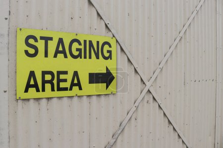 Photo for Yellow and black Staging Area sign with arrow on the corrugated iron door at an airport - Royalty Free Image