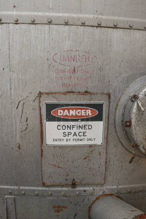 Photo for Red, black and white Danger, Confined Space warning sign on the metal entrance door of a silo - Royalty Free Image