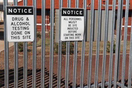 Photo for Black and white Notice, Drug and Alcohol Testing Done on This Site and All Personnel Must Be Site Inducted Before Starting Work On This Site metal warning signs on the exterior of a workplace boundary fence - Royalty Free Image