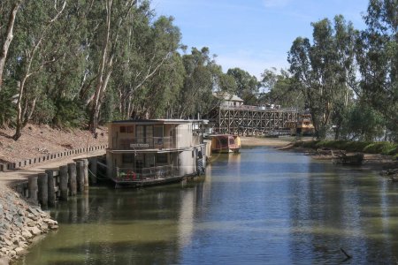 Photo for ECHUCA, AUSTRALIA - March 1, 2020: looking past moored river boats on the Murray River towards the historic red gum wharf at Echuca - Royalty Free Image