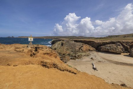 Foto de Vista del puente natural colapsado y señal de peligro de un mayor colapso de la costa rocosa Océano Atlántico. Aruba.. - Imagen libre de derechos