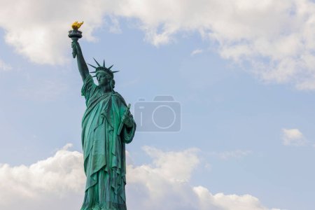 Beautiful view of Statue of Liberty on Liberty island in New York against blue sky with white clouds.
