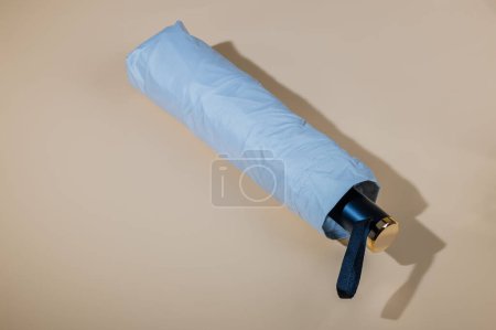 Photo for Close-up view of silver colored sun umbrella in slipcover with uv protection spf50+ isolated on beige background. - Royalty Free Image