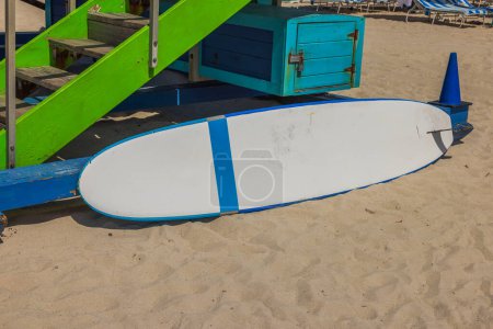 Photo for View of surfboard lying near water guard station on Miami Beach. Water sports equipment. USA. - Royalty Free Image