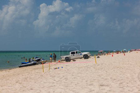 Photo for White Jeep parked near water scooters on Miami Beach on front and people enjoying Atlantic Ocean under sunny blue sky. Miami Beach. USA. - Royalty Free Image