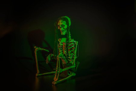 Foto de Vista de cerca del esqueleto de juguete sonriente con retroiluminación verde sobre fondo negro. concepto de decoración de Halloween. Países Bajos. - Imagen libre de derechos