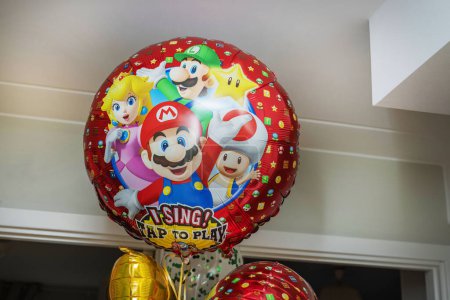 Foto de Escena encantadora con grandes globos llenos de helio con personajes de dibujos animados favoritos dentro de un acogedor apartamento, trayendo alegría y diversión a la habitación. - Imagen libre de derechos
