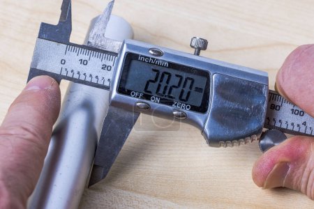 Photo for Man is using electronic caliper to measure size of aluminum pipe. - Royalty Free Image
